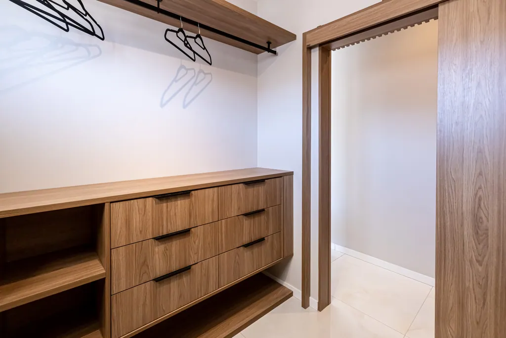 Closet da suíte master com gaveteiros e araras em madeira