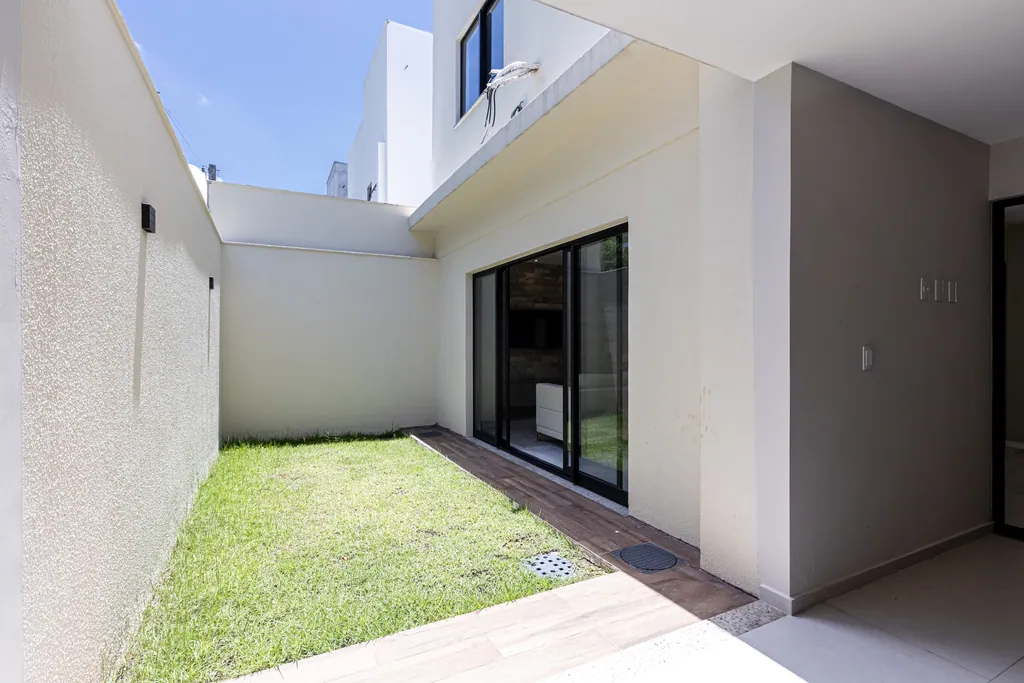 Quintal gramado nos fundos da casa, ligado à sala por portas de vidro