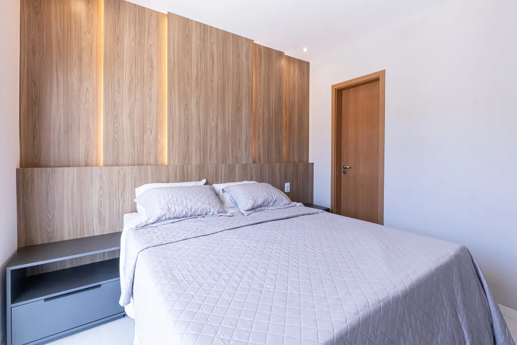 Suíte master com cabeceira em painel de madeira iluminado e cama de casal